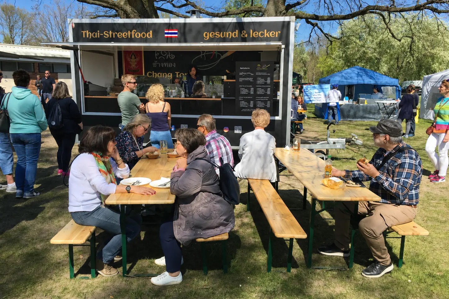 Gäste an Tischen vor dem Chang Tong Foodtruck