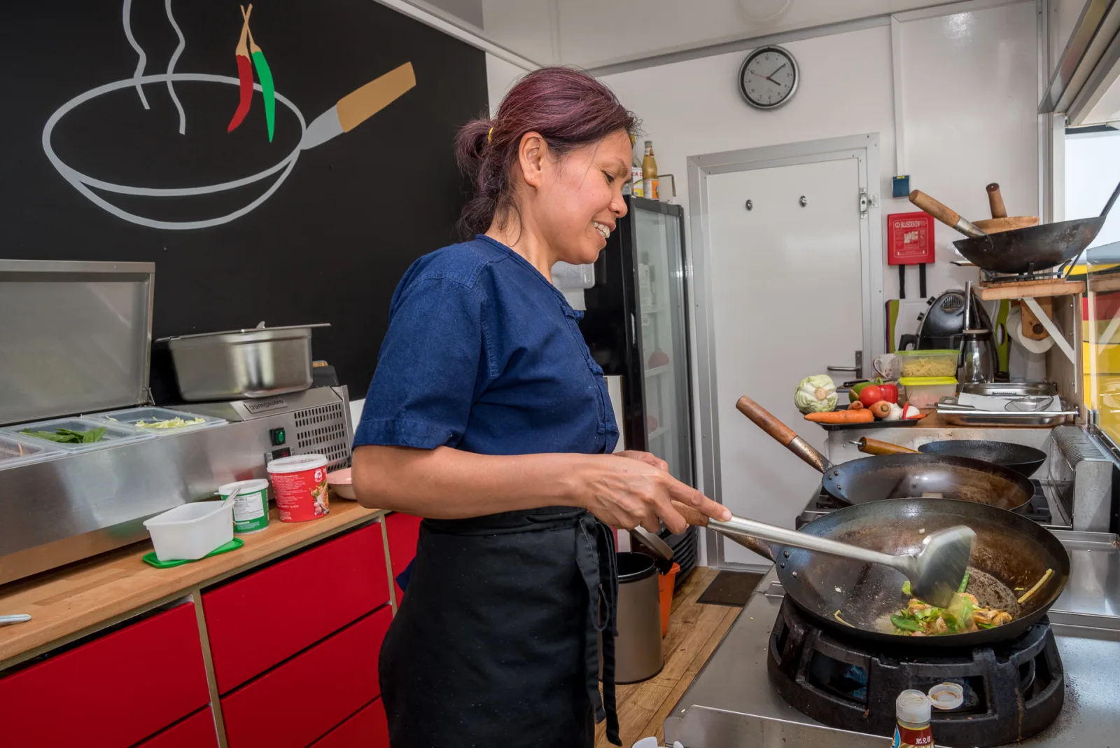 Patinya Busch bereitet ein Gericht frisch im Wok zu